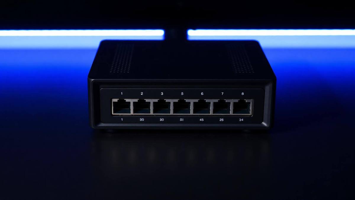 Compact multi-port network security appliance photographed on a dark surface with blue lighting