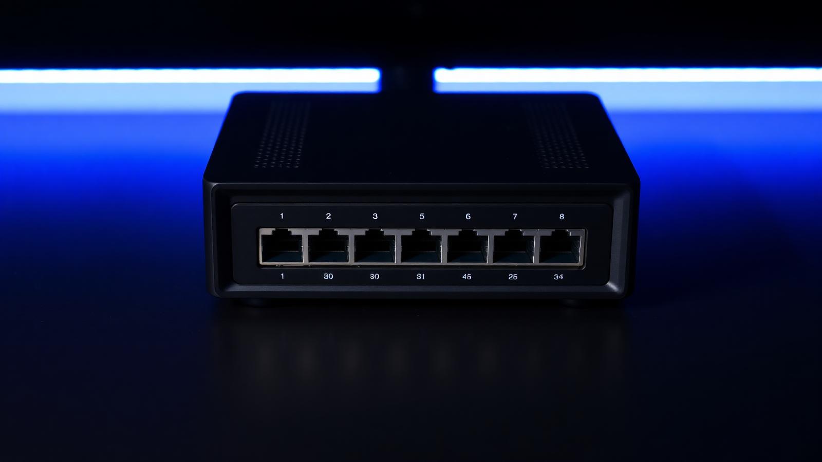 Compact multi-port network security appliance photographed on a dark surface with blue lighting